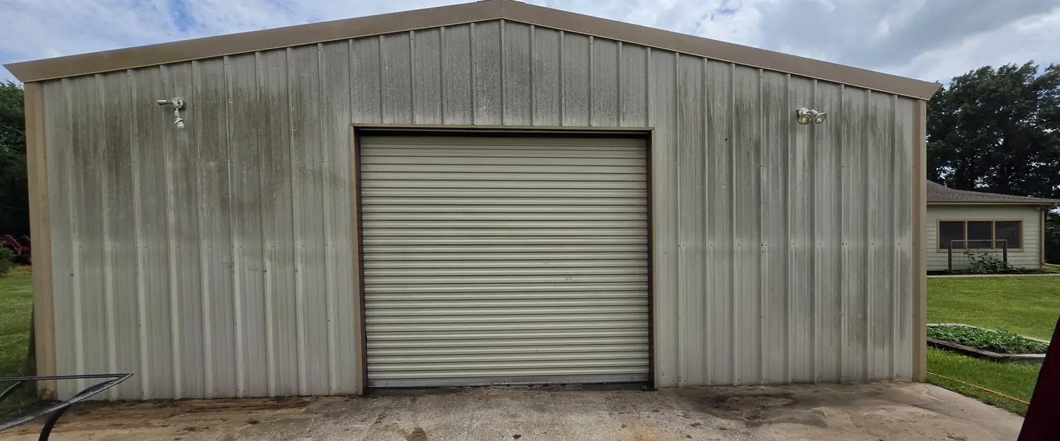 Before: metal shop building with dark mildew streaks down the wall panels