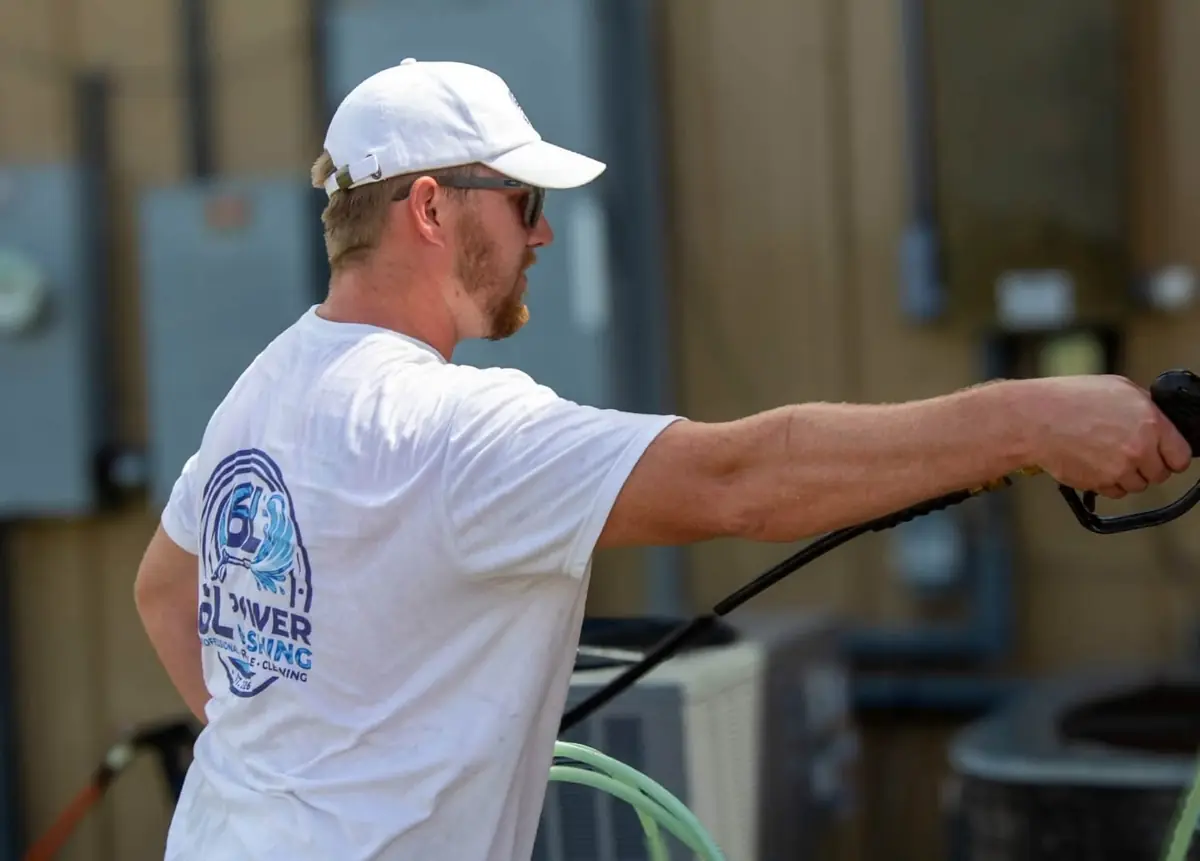 Spraying with a pressure washer gun, the 6L Power Washing logo printed on the back of the T-shirt